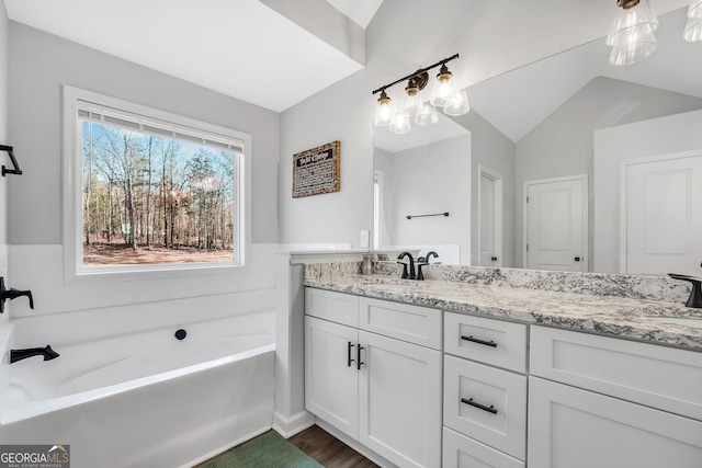 bathroom featuring hardwood / wood-style flooring, lofted ceiling, vanity, and a bathtub