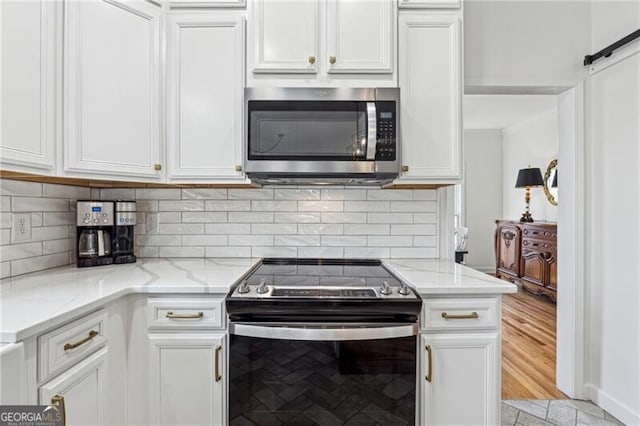 kitchen with tasteful backsplash, appliances with stainless steel finishes, a barn door, light stone countertops, and white cabinets