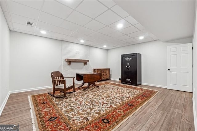 living area with wood-type flooring and a paneled ceiling