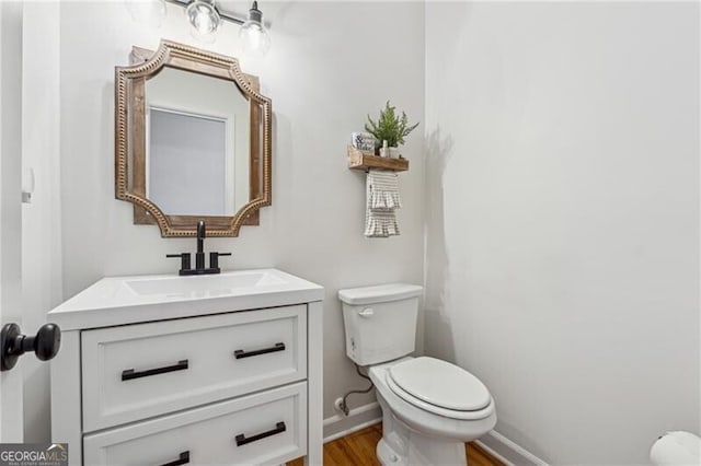 bathroom with hardwood / wood-style flooring, vanity, and toilet