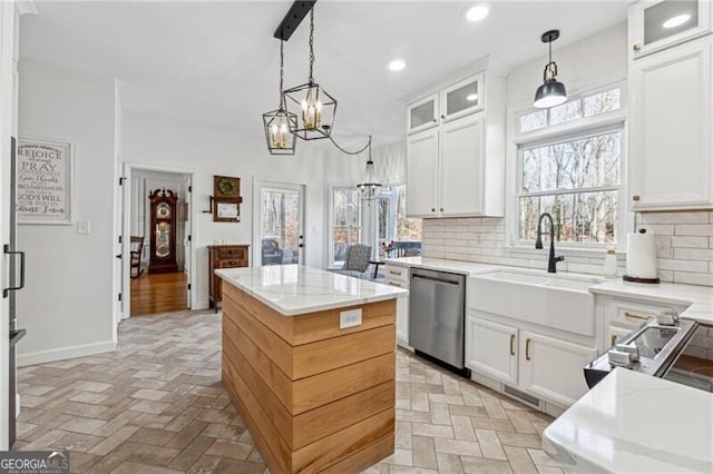 kitchen featuring dishwasher, sink, a kitchen island, and white cabinets