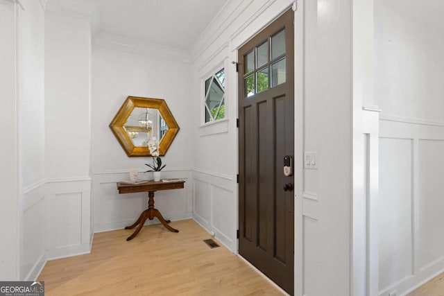 entryway featuring crown molding and light wood-type flooring