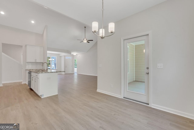 kitchen featuring sink, white cabinetry, decorative light fixtures, light wood-type flooring, and an island with sink