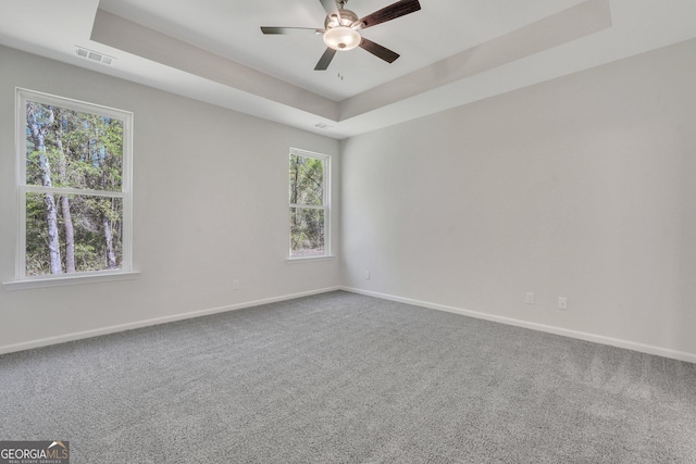 carpeted empty room with ceiling fan and a tray ceiling