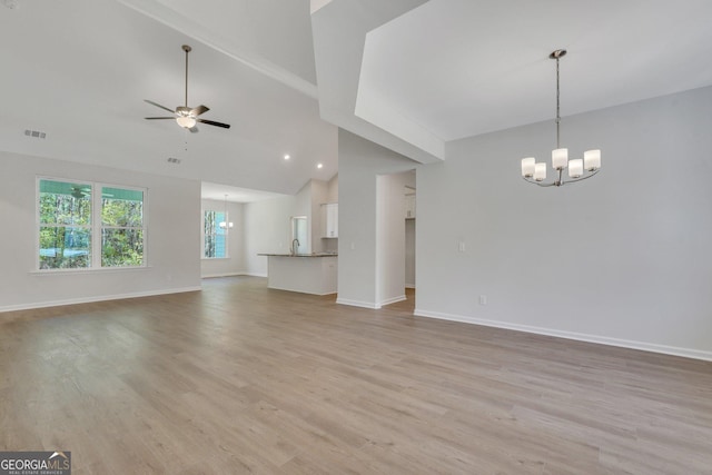 unfurnished living room featuring a chandelier, light wood-style floors, a ceiling fan, baseboards, and lofted ceiling