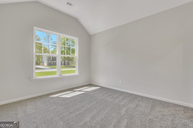 unfurnished room featuring healthy amount of natural light, carpet, vaulted ceiling, and baseboards