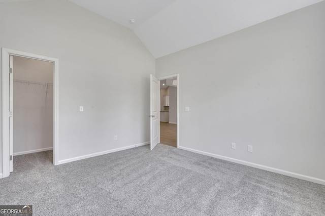 unfurnished bedroom with a walk in closet, carpet floors, lofted ceiling, baseboards, and a closet