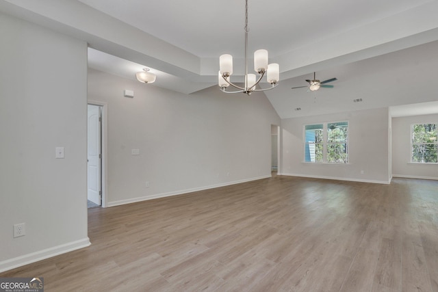 empty room featuring vaulted ceiling, ceiling fan with notable chandelier, and light hardwood / wood-style flooring