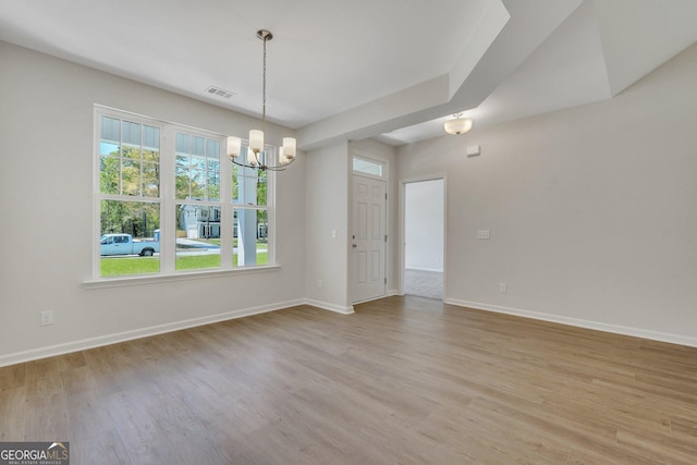 unfurnished room featuring an inviting chandelier and light wood-type flooring