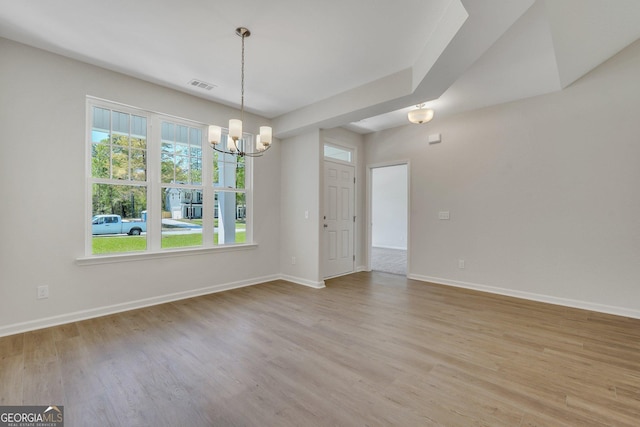unfurnished dining area featuring a chandelier, light wood-type flooring, and baseboards