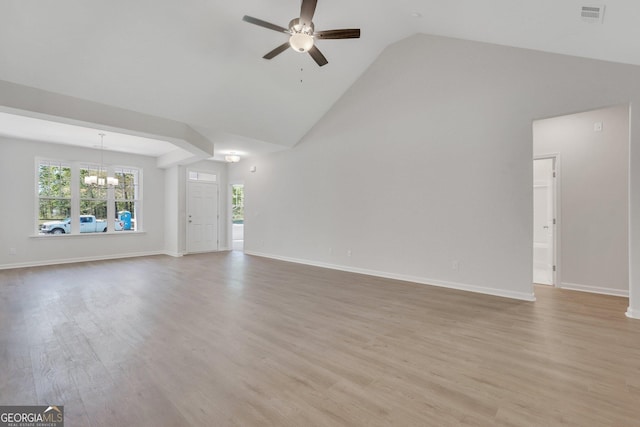 unfurnished living room with high vaulted ceiling, ceiling fan with notable chandelier, and light wood-type flooring