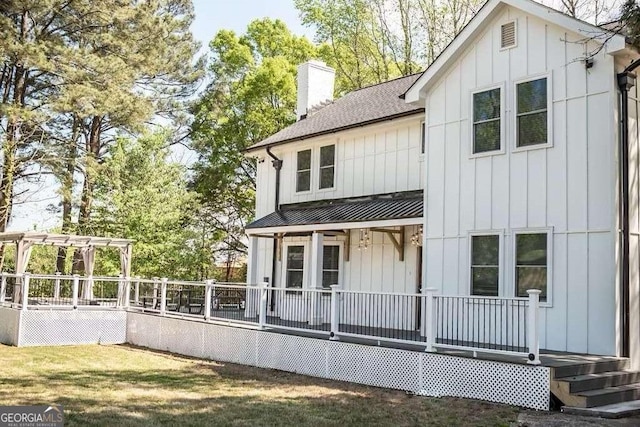 rear view of property featuring a lawn and a pergola