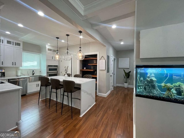 kitchen with stainless steel appliances, decorative light fixtures, a kitchen island, and white cabinets