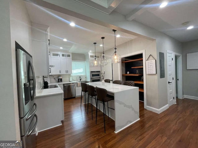 kitchen with appliances with stainless steel finishes, white cabinets, a kitchen island, dark hardwood / wood-style flooring, and decorative light fixtures