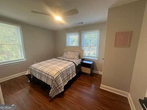 bedroom featuring ceiling fan, dark hardwood / wood-style flooring, and multiple windows