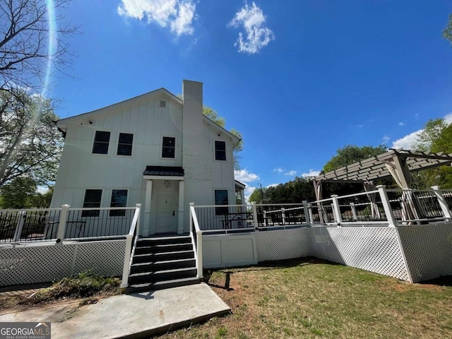 back of property with a pergola and a lawn