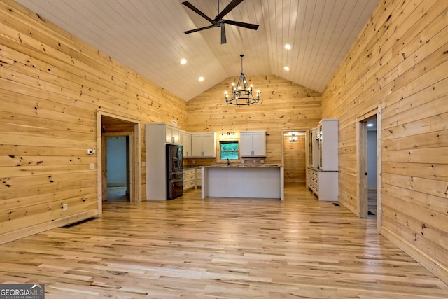 kitchen featuring pendant lighting, a center island, light hardwood / wood-style floors, white cabinets, and wood walls