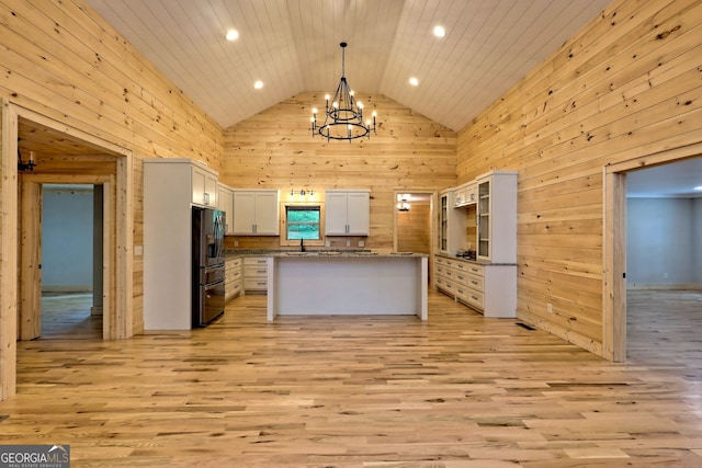 kitchen featuring a center island, high vaulted ceiling, black refrigerator with ice dispenser, pendant lighting, and white cabinets