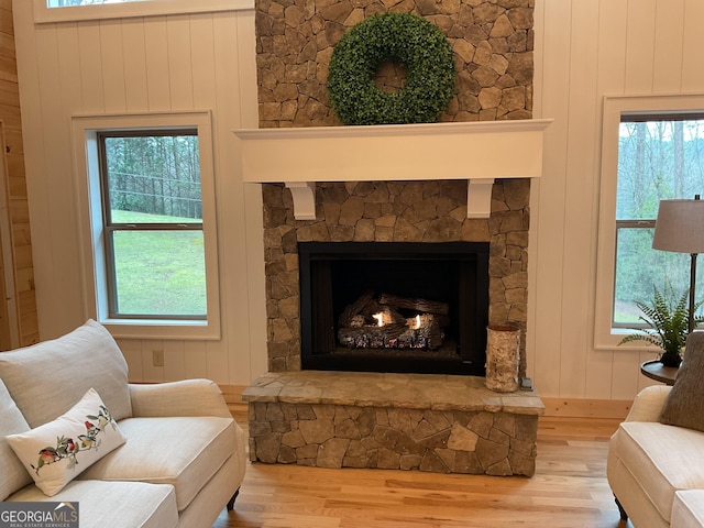 sitting room with hardwood / wood-style flooring, plenty of natural light, and a stone fireplace