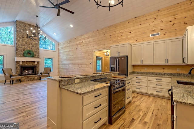 kitchen with pendant lighting, sink, stainless steel fridge, light stone countertops, and black / electric stove