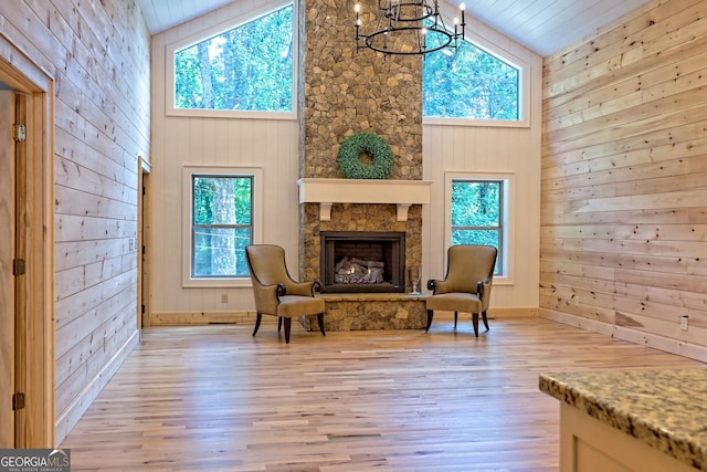 living area featuring a healthy amount of sunlight, a stone fireplace, and light hardwood / wood-style flooring