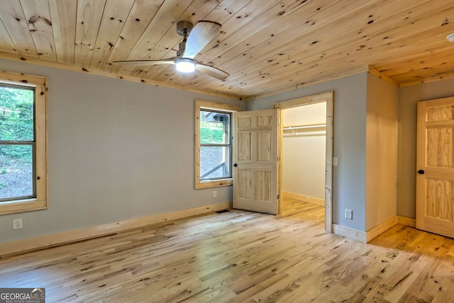 unfurnished bedroom with light wood-type flooring, a spacious closet, and wood ceiling