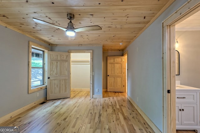 unfurnished bedroom with light hardwood / wood-style floors, wood ceiling, a walk in closet, and a closet