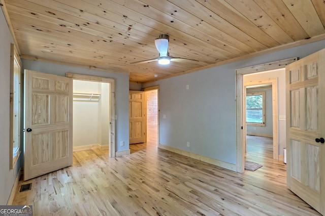 unfurnished bedroom featuring light hardwood / wood-style floors, a closet, wooden ceiling, and a spacious closet