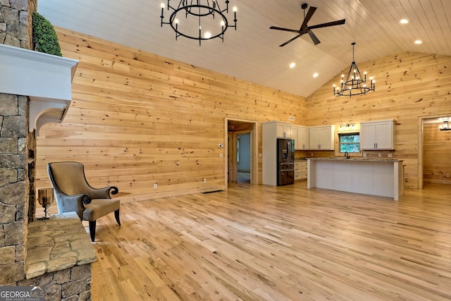 interior space with wooden walls, high vaulted ceiling, light hardwood / wood-style floors, ceiling fan with notable chandelier, and wooden ceiling