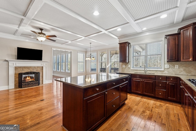 kitchen featuring backsplash, hanging light fixtures, coffered ceiling, a center island, and light wood-type flooring