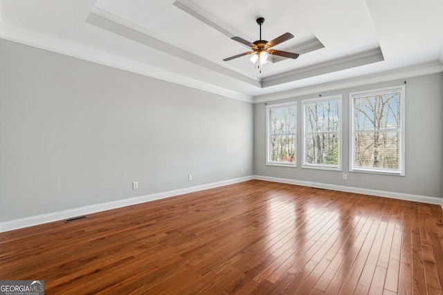 spare room featuring ceiling fan, ornamental molding, wood-type flooring, and a raised ceiling