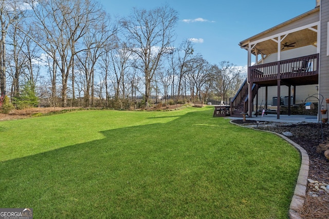 view of yard with ceiling fan and a deck