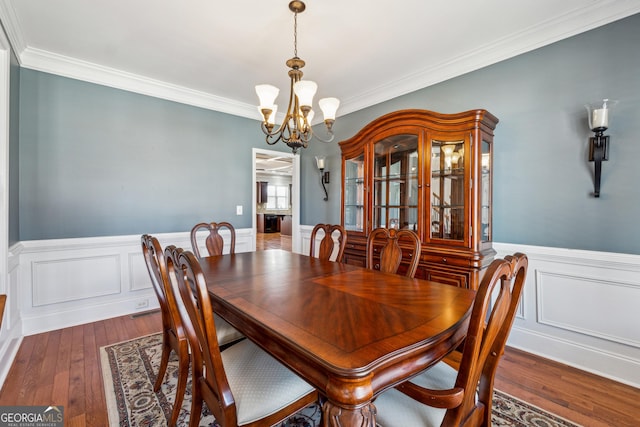 dining space featuring an inviting chandelier, crown molding, and dark hardwood / wood-style floors