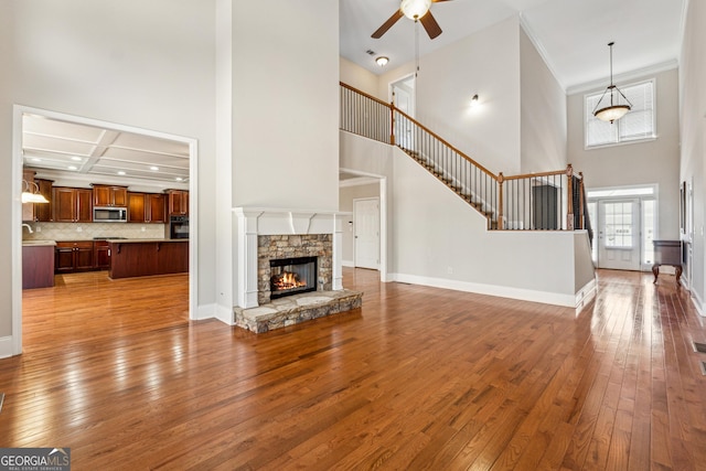 living room featuring coffered ceiling, crown molding, light wood-type flooring, ceiling fan, and a fireplace