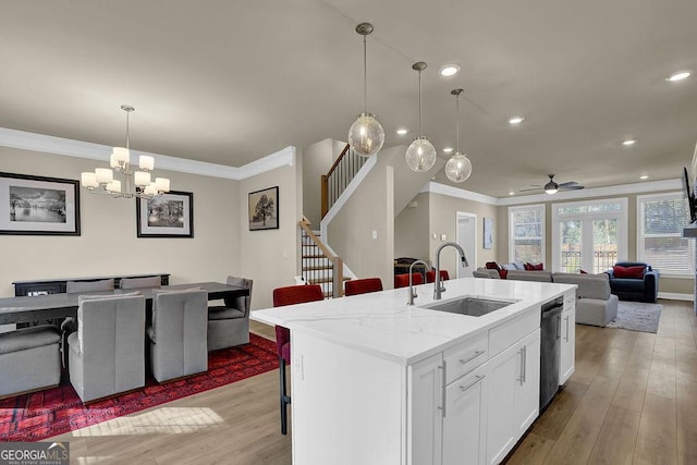 kitchen featuring sink, light stone counters, a center island with sink, light hardwood / wood-style floors, and white cabinets