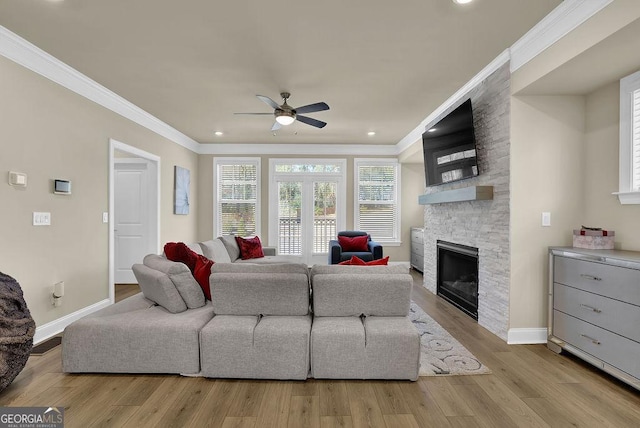 living room featuring a fireplace, ornamental molding, ceiling fan, and light wood-type flooring