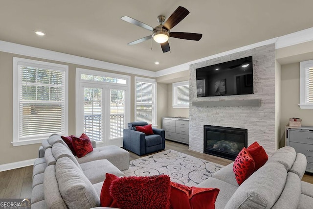 living room with a stone fireplace, light hardwood / wood-style floors, and ceiling fan