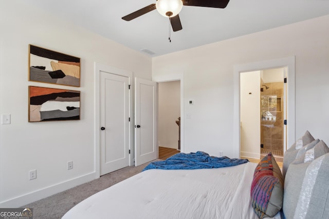 carpeted bedroom with ensuite bath and ceiling fan