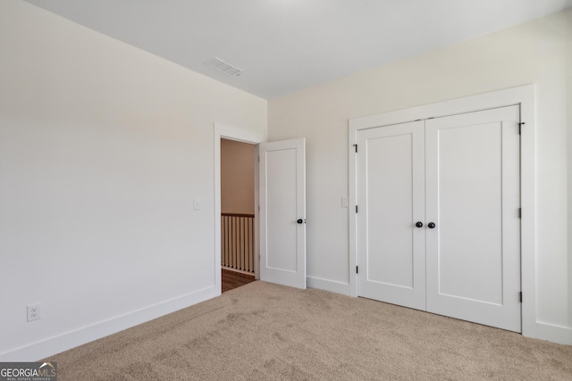 unfurnished bedroom with a closet and light carpet