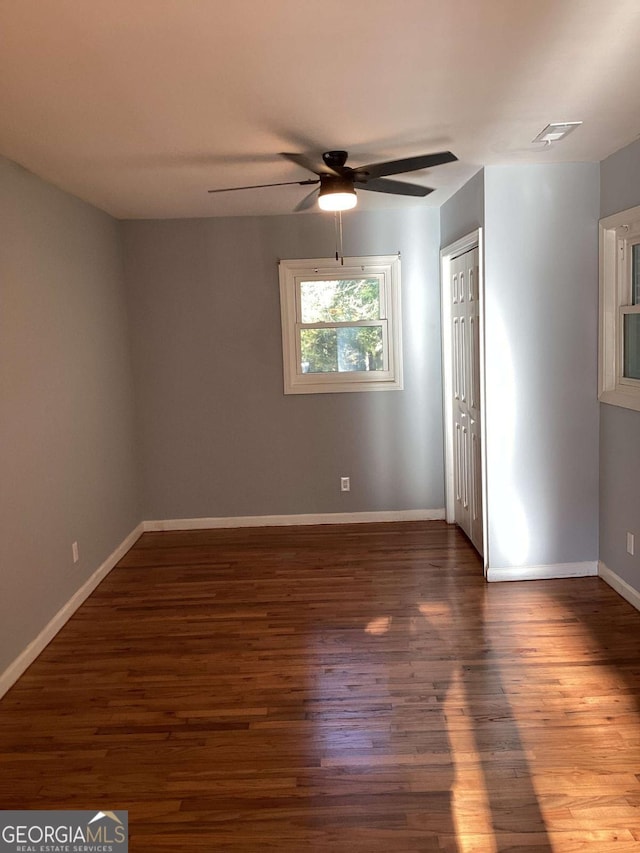 empty room with dark hardwood / wood-style floors and ceiling fan