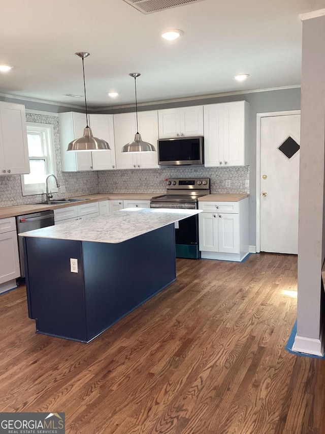 kitchen with sink, white cabinetry, a center island, appliances with stainless steel finishes, and pendant lighting