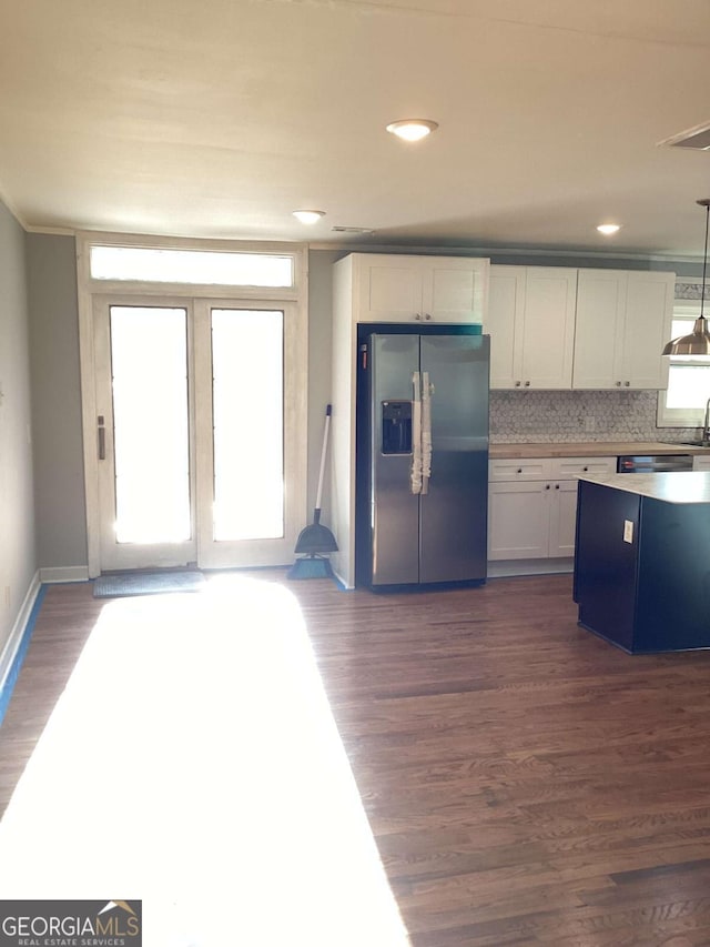 kitchen featuring dark wood-type flooring, stainless steel fridge, decorative light fixtures, and white cabinets