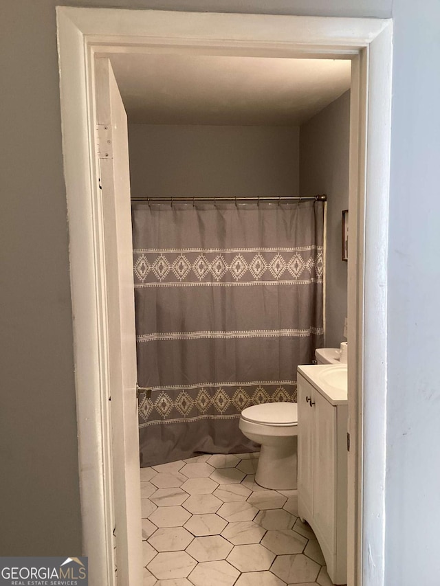 bathroom featuring a shower with curtain, vanity, toilet, and tile patterned flooring