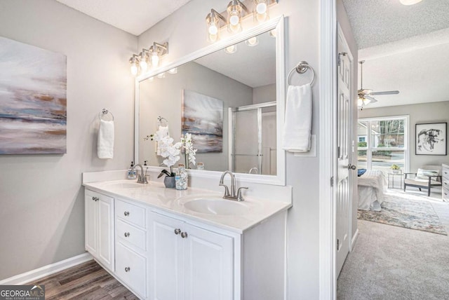 bathroom with hardwood / wood-style flooring, ceiling fan, vanity, a textured ceiling, and a shower with shower door