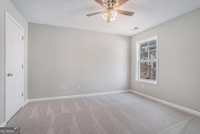 empty room featuring ceiling fan, carpet, and a textured ceiling