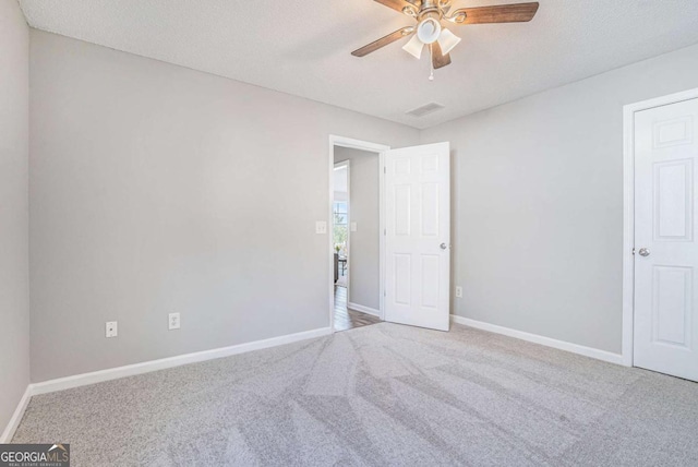 unfurnished room featuring a textured ceiling, light colored carpet, and ceiling fan