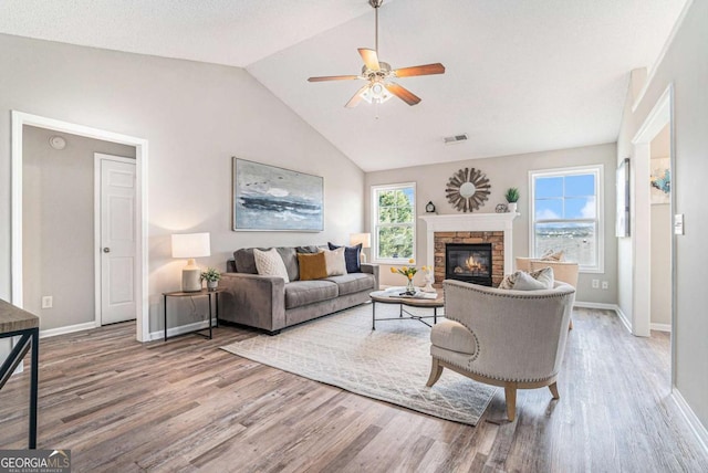 living room with lofted ceiling, hardwood / wood-style floors, a fireplace, and ceiling fan