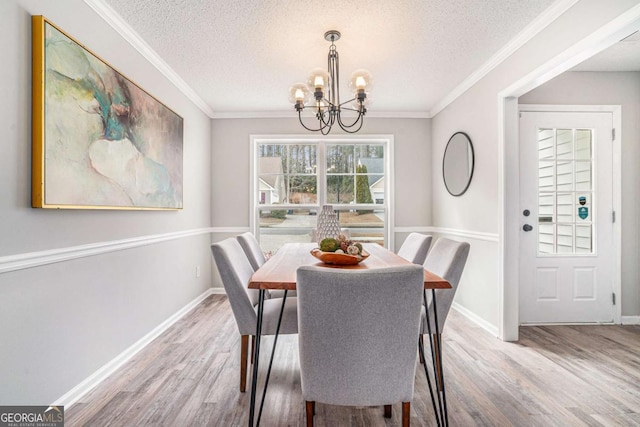 dining space with an inviting chandelier, crown molding, and wood-type flooring