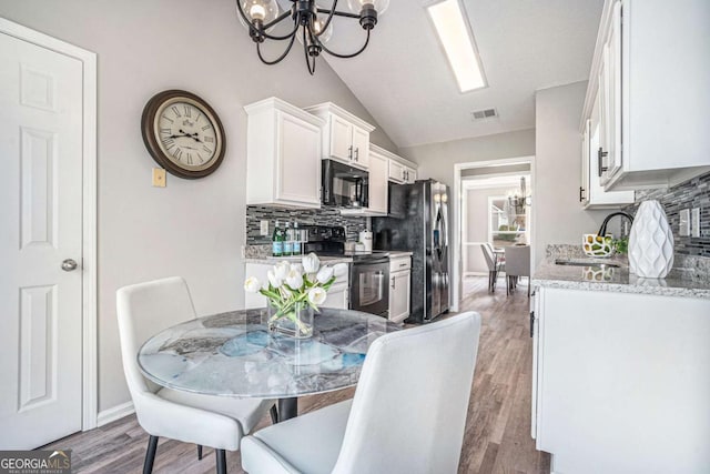 dining area with lofted ceiling, sink, a chandelier, and light hardwood / wood-style flooring