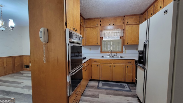 kitchen with pendant lighting, sink, black oven, white fridge with ice dispenser, and oven